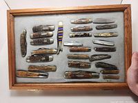 Overhead view of all pocket knives arranged in wooden case