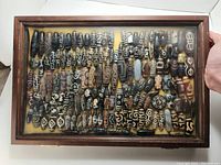 Wooden framed glass display case with yellow felt lining showing arranged Tibetan Dzi beads