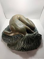 Top-down view showing the curved back and textured base of the bronze sculpture