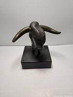 Front view of bronze sculpture head with horns on wood base