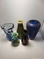 Front view of all five art glass vases displayed side by side