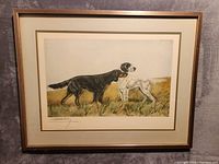Framed watercolor painting showing two setters in a grassy field with signature visible in corner.