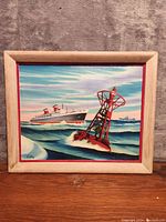 Full view of the oil painting showing the ship, buoy, ocean, sky, and wooden frame with red trim