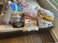 Overview of all blankets, sheets and pillow items stacked on a mattress.