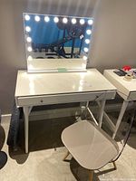 Front view of white desk with drawer, light-up vanity mirror on top, and acrylic chair in front