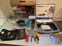 Full lot showing Dremel 300 kit in case, mixed hand tools, and toolkit pouch