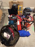 Overview photo of lot showing cycling shoes, resistance bands, wrist weights, jump rope, and hats on floor.