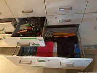 Drawers partially open showing assortment of flashlights and folded bags inside.