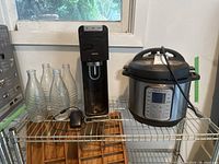 Instant Pot, Sodastream, and glass bottles on metal shelf near window