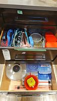 Drawer open showing plastic storage containers and insulated lunch bags organized side by side