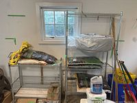 View showing two metal wire shelving units with various gardening and household items stored on shelves