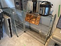 Front view of three metal wire shelving racks, some items on one rack but contents not included in sale.