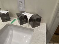 Two black square boxes of scented candles, one labeled Jasmin, the other Figue, both unopened and shown on a bathroom counter.