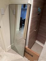 Full-length mirror leaning against wall in basement hallway