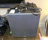 Front view of the Polk Audio subwoofer with cords on top.