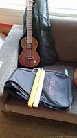 Oscar Schmidt ukulele with soft case and black Odyssey bag on couch