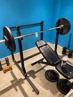 Full view of bench, rack, barbell loaded with plates, dumbbells and accessories