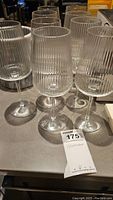Eight vertical ribbed pattern crystal wine glasses on table, showing clear stems and bases.