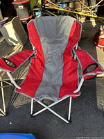 Red and gray folding camping chair with metal frame, fabric seating and armrests with cup holders