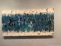 Front view of rectangular coated canvas abstract wall art in blues and greens mounted on wall.