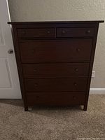 Front view of a brown IKEA dresser with six drawers: 2 smaller drawers on top, 4 larger drawers below, all with round knobs.