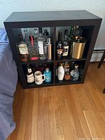 Front view of the IKEA Kallax cube shelf unit filled with assorted bottles and containers, showing 4x4 grid compartments.
