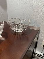Clear crystal bowl with scalloped edges and cut star-like pattern on a wooden surface