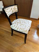 Side view of upholstered side chair showing black frame and leaf patterned upholstery