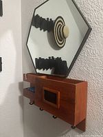 Side angle view showing hexagonal mirror above the wooden organizer with hooks and small cubby containing items.