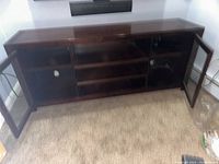 Front view of wood entertainment console with both glass doors open showing shelving inside.