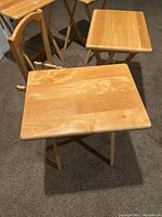 Photo showing four wooden folding tables with rectangular tops and folding legs standing together, highlighting the natural finish and grain of the wood.