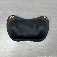 Front view of black heated head massager with breathable mesh fabric and orange control buttons on corners.