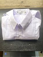 Folded white child's dress shirt with visible YuanLu brand tag, showing pleated chest design and classic collar