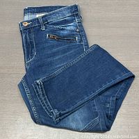 Folded pair of H&M skinny fit jeans in medium blue wash with a zipped coin pocket visible.