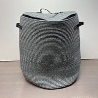 Front view of the large gray woven laundry basket with zipper lid closed, displaying its size and shape.