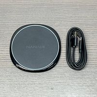Top-down view of Nanami wireless charger alongside black USB-C cable, showing the charging pad details and cable ends.