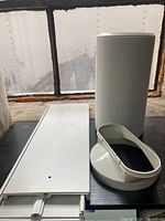 White extendable window kit panel, flexible exhaust hose, and plastic adapter ring, arranged on a dark surface by a window.