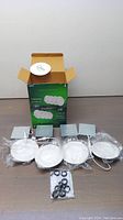 Full set of eight Qplus 4-inch LED slim panel recessed pot lights, all individually wrapped, with box and accessories on table.