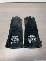 Full view of pair of Rapicca black welding gloves displayed palm down, showing logos and size markings
