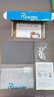 Box containing Realyou grounding pillowcase in gray fabric, grounding cable with wire connectors, instruction sheet, and white pouch bag with Realyou branding.