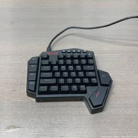 Front angled view of the Redragon DITI Elite mechanical gaming keypad on a wooden surface, showing custom key configuration and macro keys along the left side.