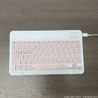 Top view of the keyboard showing pink keys in white frame on a wood surface.