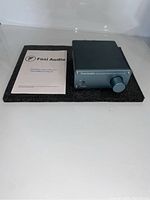 Unit with user manual lying on a black foam mat, showing amplifier and documentation.