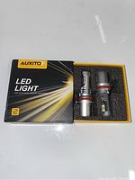 Box of two AUXITO LED vehicle lights in black and yellow branded packaging.