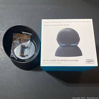 Photo showing the battery base alongside the product box and included adapter in the center compartment.