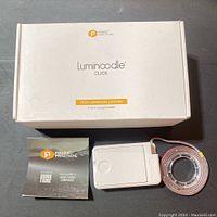 Photo of the opened Luminoodle Click LED light kit box with one LED strip coiled and battery pack alongside instruction booklet.