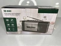 Box front showing product image and main features like AM/FM radio, cassette player, and headphone jack.