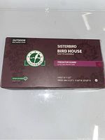 Box top showing Sisterbird Bird House branding, easy to assemble, predator guard noted, and outdoor use tag.