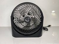 Front side view of black USB fan with three blades and USB cable visible, showing the fan face and logo.