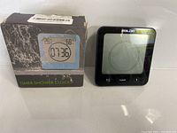 Photo showing BALDR shower timer next to original product box with timer's image and model information.